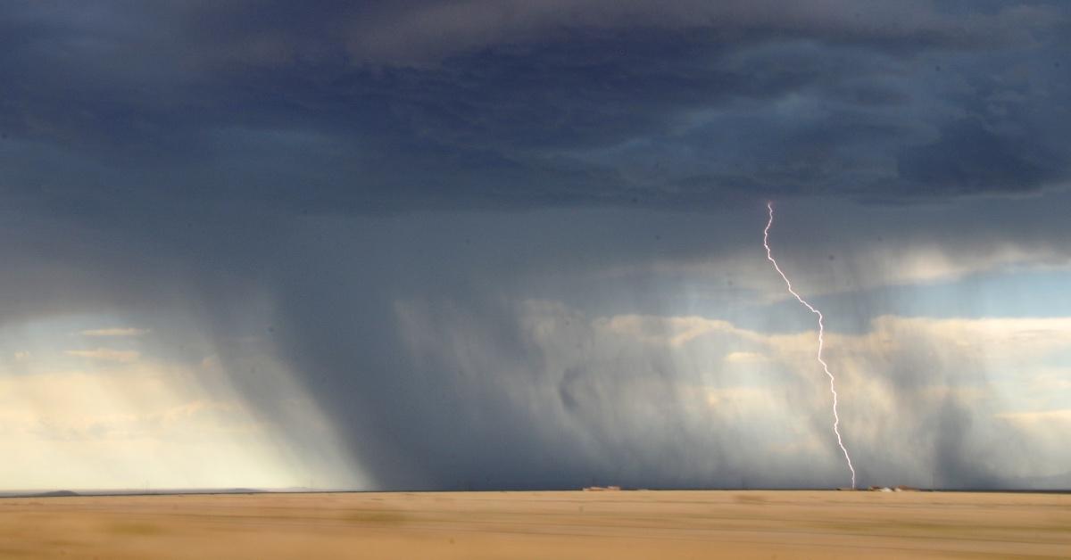 Photograph of a tornado landing with a bolt of lightning. 