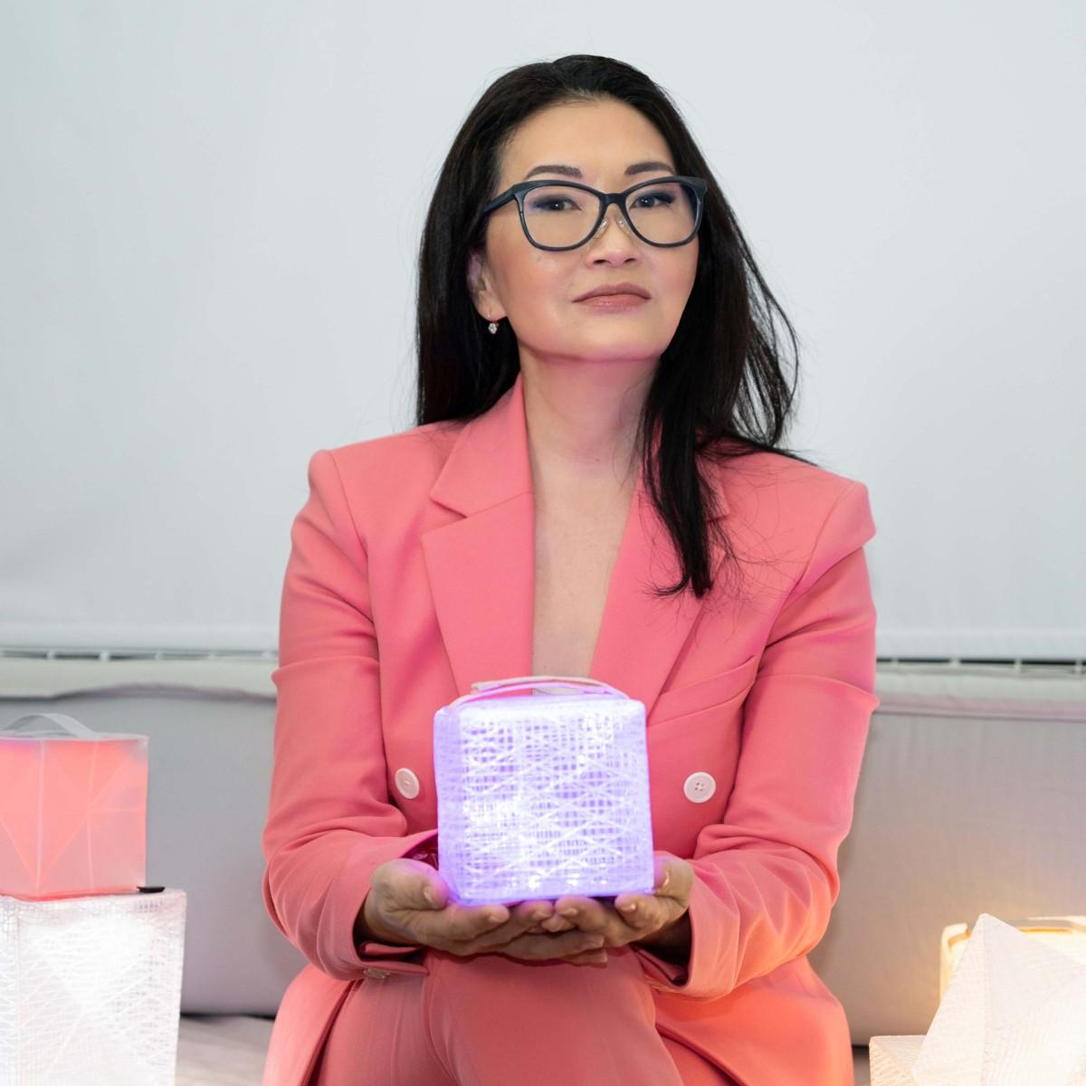 Photo of Solight Design CEO and founder Alice Chun wearing a pink suit and holding a solar lantern